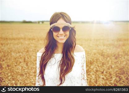nature, summer, youth culture and people concept - smiling young hippie woman in sunglasses on cereal field
