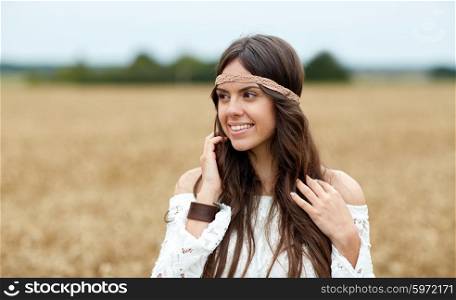 nature, summer, youth culture and people concept - smiling young hippie woman on cereal field