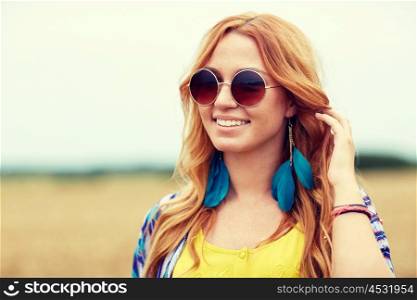 nature, summer, youth culture and people concept - smiling young redhead hippie woman in sunglasses outdoors
