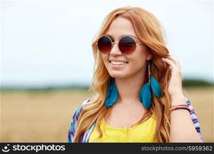 nature, summer, youth culture and people concept - smiling young redhead hippie woman in sunglasses outdoors
