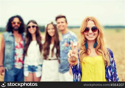 nature, summer, youth culture, gesture and people concept - smiling young hippie friends in sunglasses showing peace hand sign on cereal field