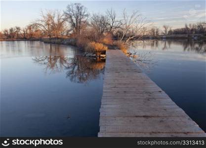 nature trail - boardwalk pathway over lake in old gravel quarry converted into park (Riverbend Ponds in Fort Collins, Colorado), late fall or early winter scenery with some snow and ice