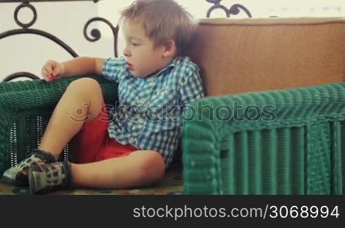 Naughty little boy in the armchair on the balcony