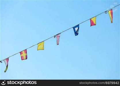 Nautical flags waving on wind against blue sky. National and travel concept.