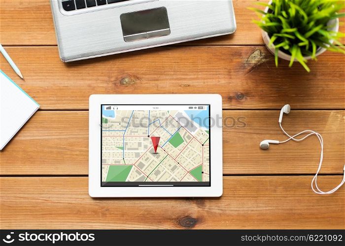 navigation, location, business and technology concept - close up of tablet pc computer, laptop and earphones on wooden table with gps navigator map
