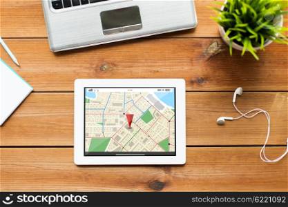 navigation, location, business and technology concept - close up of tablet pc computer, laptop and earphones on wooden table with gps navigator map
