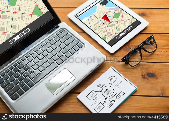 navigation, responsive design and technology concept - close up of on laptop computer, tablet pc, notebook and eyeglasses with gps navigator map and scheme on wooden table