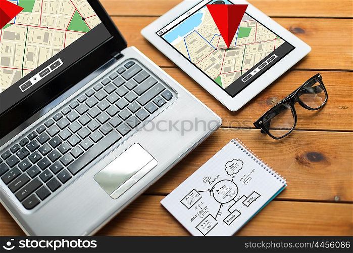 navigation, responsive design and technology concept - close up of on laptop computer, tablet pc, notebook and eyeglasses with gps navigator map and scheme on wooden table