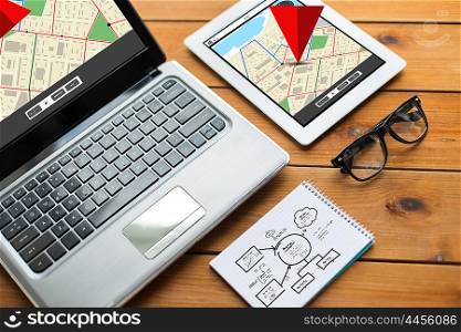 navigation, responsive design and technology concept - close up of on laptop computer, tablet pc, notebook and eyeglasses with gps navigator map and scheme on wooden table