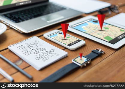 navigation, travel and technology concept - close up of laptop computer, tablet pc, notebook and smartphone with scheme and gps navigator map on wooden table