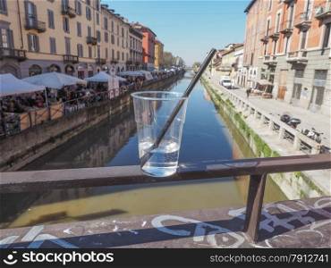 Naviglio Grande Milan. A glass of alcoholic cocktail drink on a bridge at Naviglio Grande canal waterway which is the main nightlife place in Milan Italy - focus on glass, with blurred background