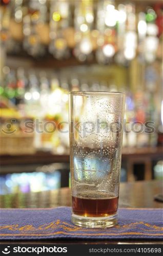 nearly empty pint glass of beer sitting on bar in a pub