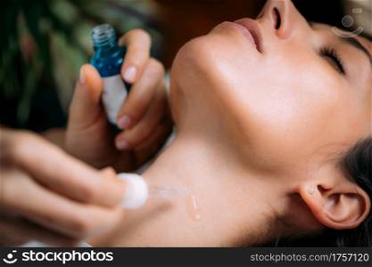 Neck anti-aging treatment. Cosmetician Applying Hyaluronic Acid Serum on Woman&rsquo;s Neck