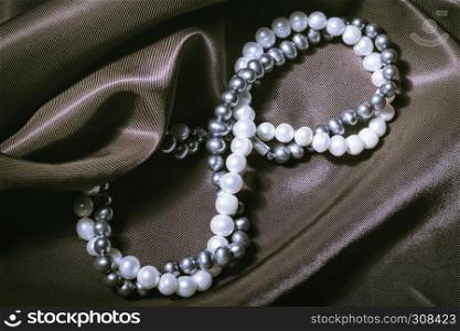 Necklaces of white and black pearls in the form of a sign of infinity on silk. Greeting card for the wedding, International Women?s Day March 8, Valentine?s and Mother?s Days.. Natural Pearl Necklaces On Silk Background