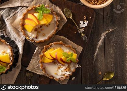 Nectarine vegan tarts with grated coconut and crunchy peanuts. Date, walnut, almond and hazelnut base.