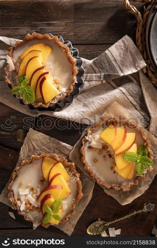 Nectarine vegan tarts with grated coconut and crunchy peanuts. Date, walnut, almond and hazelnut base.
