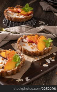 Nectarine vegan tarts with grated coconut and crunchy peanuts. Date, walnut, almond and hazelnut base.