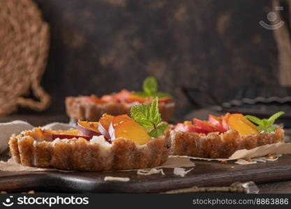 Nectarine vegan tarts with grated coconut and crunchy peanuts. Date, walnut, almond and hazelnut base.