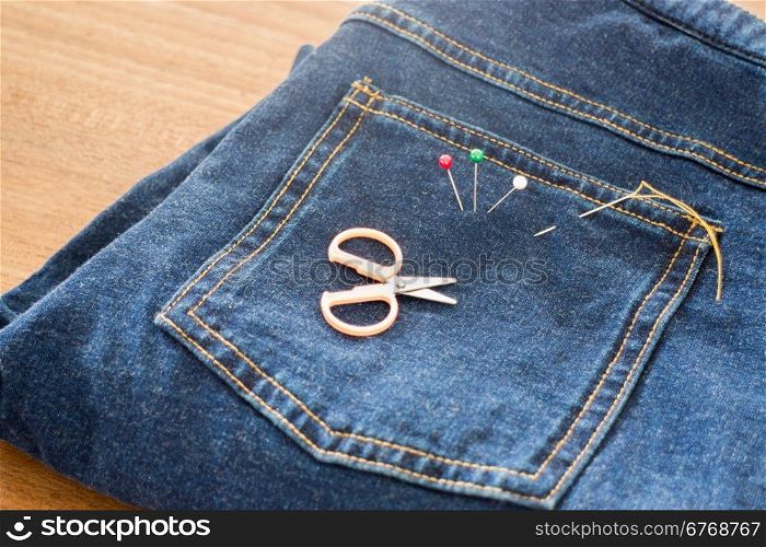 Needle with a thread through the jean, stock photo