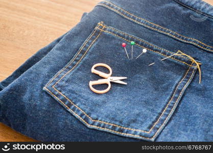 Needle with a thread through the jean, stock photo