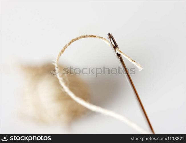 Needle with thread with ball on background