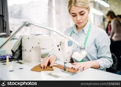 Needlewoman sews fabrics on a sewing machine. Tailoring or dressmaking on clothing factory, needlework, seamstress in workshop
