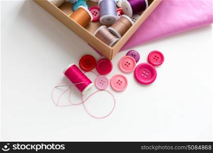 needlework, craft, sewing and tailoring concept - box with thread spools and buttons on table. box with thread spools and sewing buttons on table. box with thread spools and sewing buttons on table
