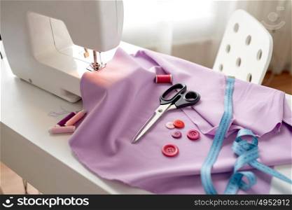 needlework, technology and tailoring concept - sewing machine with scissors, buttons, tape measure and fabric. sewing machine, scissors, buttons and fabric