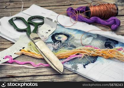 Needlework. Yarn and thread for embroidering on cloth by hand on a wooden surface.Tinted