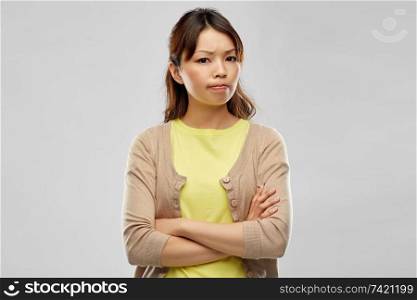 negative emotions, expressions and people concept - displeased asian woman with crossed arms over grey background. displeased asian woman with crossed arms