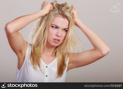 Negative emotions stress. Angry mad woman crazy furious girl pulling messy hair on gray.