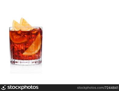 Negroni Cocktail in crystal glass with ice cubes and orange slices on white background. Space for text