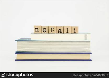 nepali word on wood stamps stack on books, language and study concept