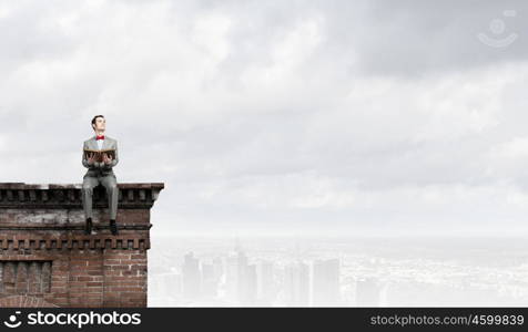 Nerd with book. Young businessman wearing red bow tie sitting with book in hands