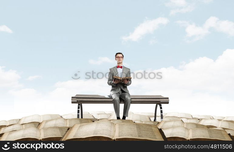 Nerd with book. Young businessman wearing red bow tie sitting with book in hands