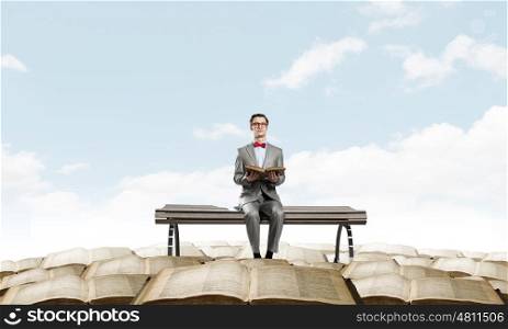 Nerd with book. Young businessman wearing red bow tie sitting with book in hands