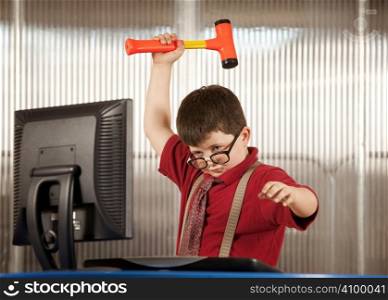 Nerdy young boy smashing his computer with a hammer