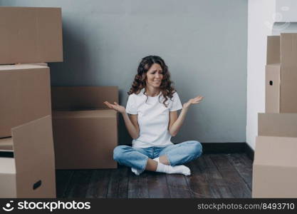 Nervous european woman has to pack the boxes. Girl is upset with moving. Annoyed young lady in jeans and white t-shirt is going to relocate. Homeowner getting stress from moving concept.. Nervous european woman has to pack the boxes. Homeowner getting stress from moving.
