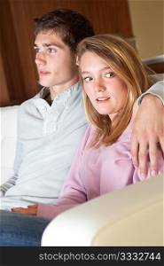 Nervous Looking Teenage Girl Sitting On Sofa At Home With Boyfriend
