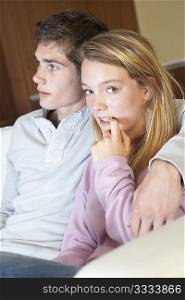 Nervous Looking Teenage Girl Sitting On Sofa At Home With Boyfriend