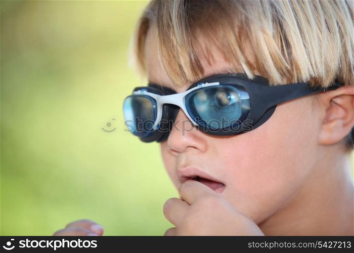 Nervous young boy wearing swimming goggles