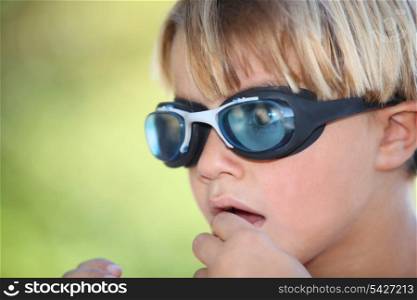Nervous young boy wearing swimming goggles