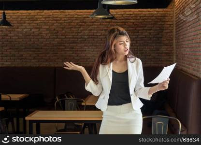nervous young frustrated asian business woman holding paper in office