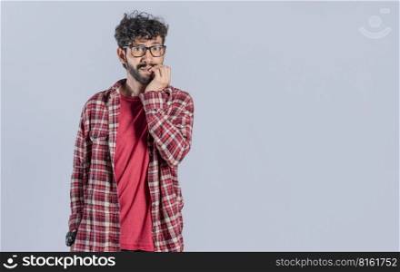 Nervous young male with worried expression, bites nails and looks anxiously. Guy with worried expression on isolated background, nervous man concept