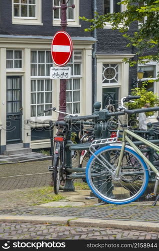 Netherlands. Amsterdam canal promenade with traditional houses and parked bicycles. Under the prohibition sign there is a sign in Dutch