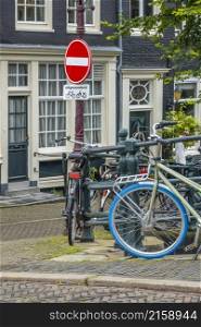 Netherlands. Amsterdam canal promenade with traditional houses and parked bicycles. Under the prohibition sign there is a sign in Dutch