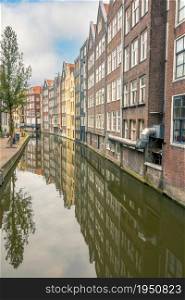 Netherlands. Amsterdam canal with industrial buildings. Reflections of houses and trees. Bicycles on the waterfront. Houses on the Canal of Amsterdam in an Industrial Area