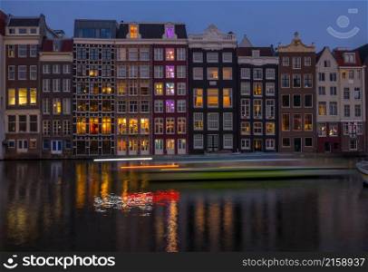 Netherlands. Classic canal houses in Amsterdam in the evening. Tourist boat in motion. Houses on the Amsterdam Canal in the Evening