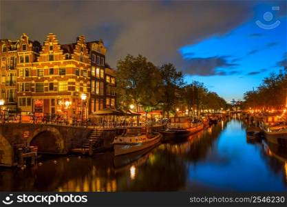 Netherlands. Evening embankment of Amsterdam. Stone bridge, bicycles near the fence and houseboats. Evening Embankment of Amsterdam