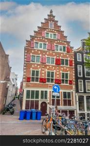 Netherlands. Narrow streets of Amsterdam with parked bikes and scooters. Typical Dutch house with red shutters on the windows. Narrow Streets of Amsterdam and Authentic House